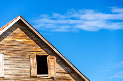 Low angle view of wooden house against blue sky