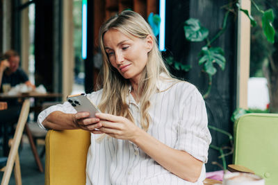 A woman uses a mobile phone to communicate while sitting in a coffee house.