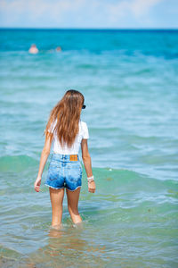 Rear view of woman standing at beach