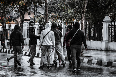 Rear view of people walking on wet street