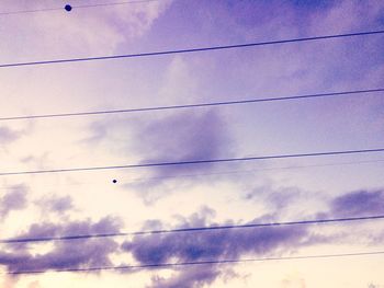 Low angle view of power lines against cloudy sky