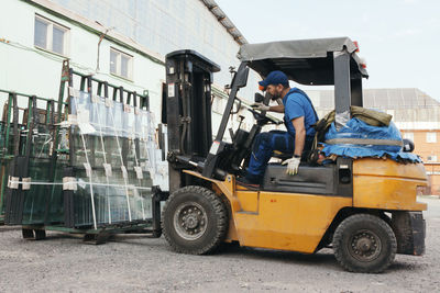 Worker driving forklift and loading glass constructions