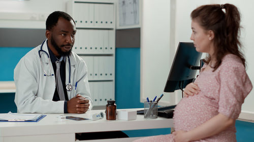 Male doctor talking to pregnant woman in clinic