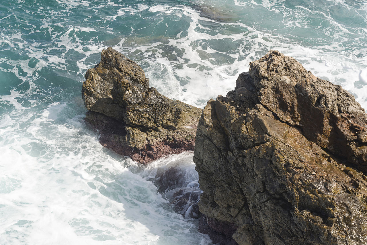 HIGH ANGLE VIEW OF ROCKS ON SHORE AT SEA