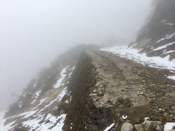 Scenic view of mountains in foggy weather against sky