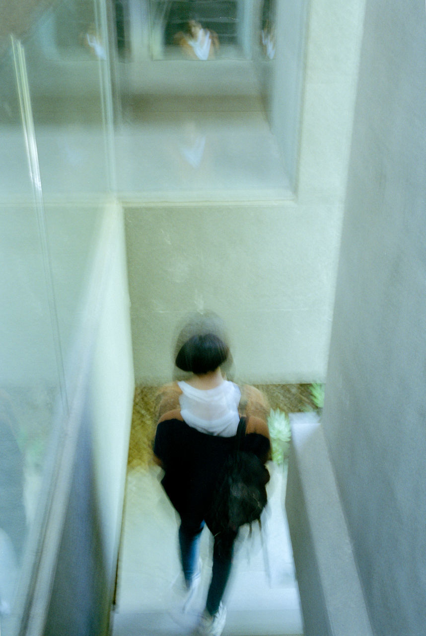 REAR VIEW OF WOMAN WALKING IN CORRIDOR OF BUILDING