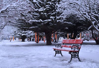 Empty bench in snow covered park during winter