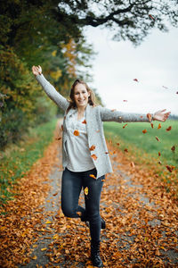 Portrait of happy woman standing in park during autumn