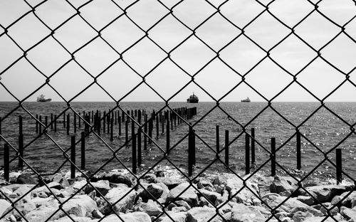 Scenic view of sea seen through chainlink fence