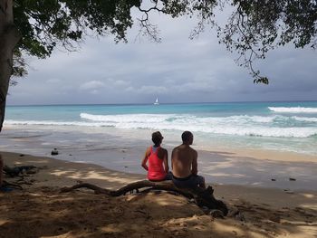 Rear view of friends sitting on beach