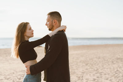 Couple standing at beach against sky