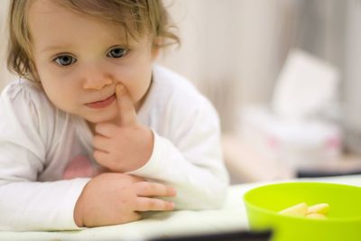 Portrait of cute baby girl sitting on table at home