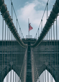 Low angle view of flag on brooklyn bridge against sky