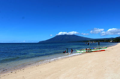 People on beach against blue sky