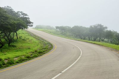 Road by trees against sky