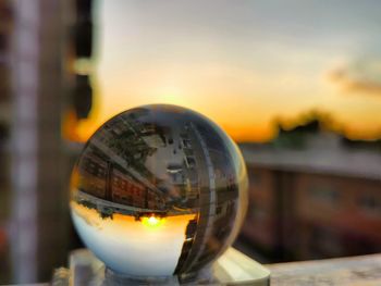 Close-up of illuminated crystal ball against building during sunset