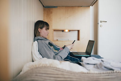 Man using mobile phone while sitting on bed