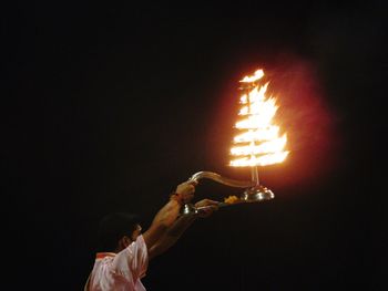 People holding illuminated fire in the dark