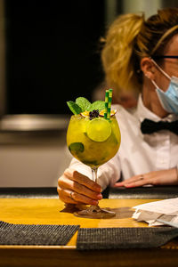 Midsection of woman drinking glass on table