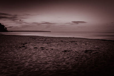 Scenic view of beach against sky at sunset