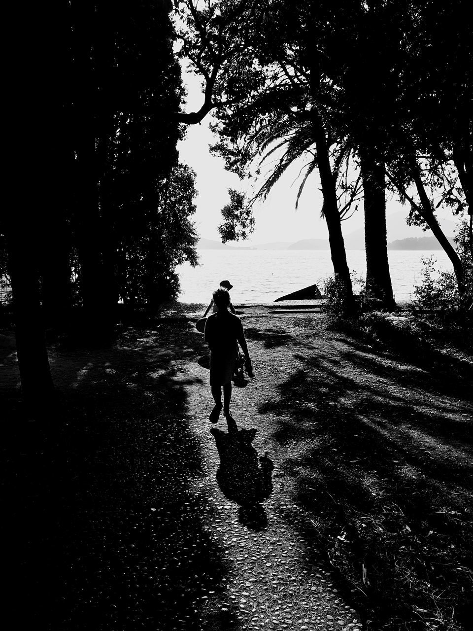 SILHOUETTE PEOPLE WALKING ON ROAD AMIDST TREES