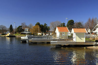 Buildings by river against clear sky