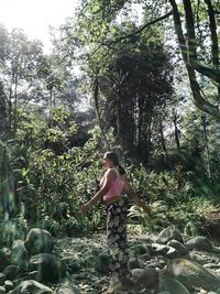 Young woman standing on tree against sky