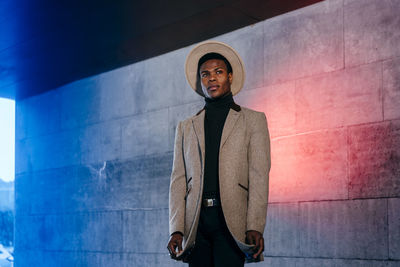 Portrait of young man standing against wall