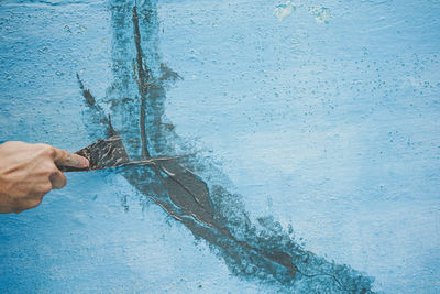 Close-up of hand holding blue wall