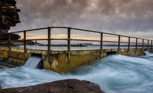 Scenic view of waterfall against cloudy sky