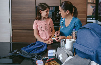 Mother preparing emergency backpack with her daughter