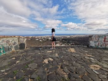 Side view of woman standing by sea against sky