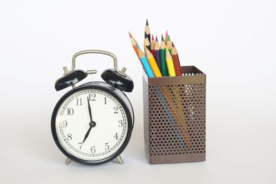 Close-up of clock on table against white background