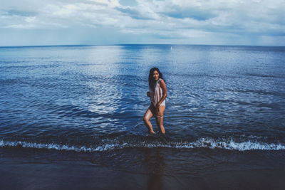 Woman standing in sea against sky