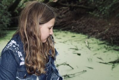 Close-up of girl looking pond in forest