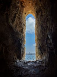 Rock formations by sea seen through hole