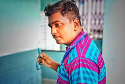 Portrait of young man standing against wall