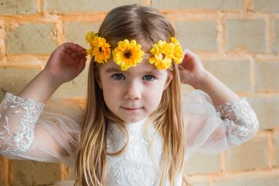 Portrait of small girl with yellow flowers on her hair. 