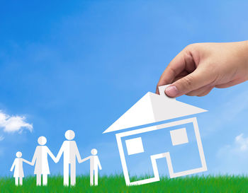 Low section of man holding umbrella against building against blue sky