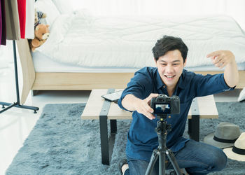 Man photographing while sitting on bed