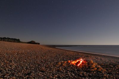 Bonfire on seashore against star field at dusk