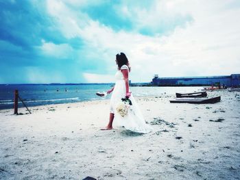 Woman standing on beach against sky