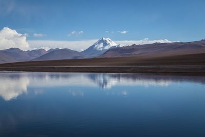 Scenic view of lake and mountains against blue sky