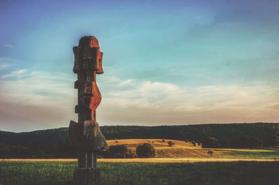 Traditional windmill on field against sky during sunset