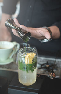 Cropped image of person holding wine glass on table