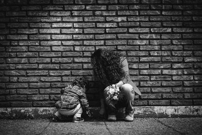 Rear view of girl sitting on brick wall