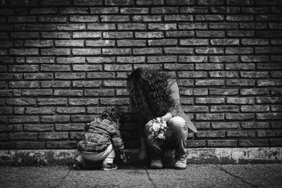 Rear view of girl sitting on brick wall