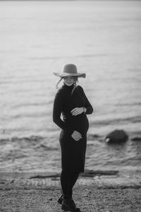 Beautiful young pregnant woman in a black turtleneck and black tight skirt, a classic beige hat 