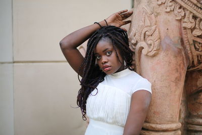 Portrait of beautiful young woman standing against wall