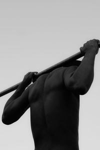 Rear view of shirtless man against clear sky